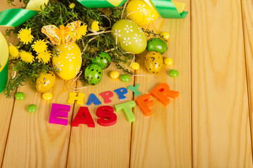 Various eggs, flowers, butterfly, ribbon, words HAPPY EASTER on light wood.