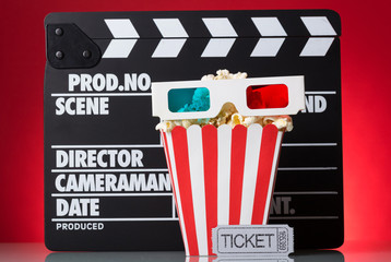 Paper square box popcorn, 3D-glasses, movie tickets and clapperboard on bright red.