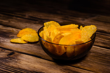 Potato chips in glass bowl on wooden table