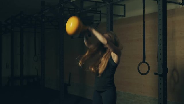 Beautiful young woman training with kettlebell weight in gym. Locked down real time 4K video.
