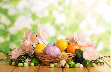 Colorful Easter eggs in basket and near, candy, grass, flowers.
