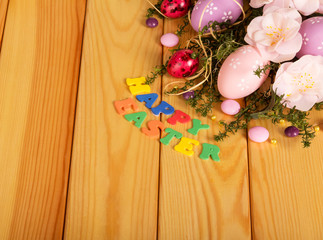 Eggs, candy, flowers, grass, words Happy Easter in light wood.