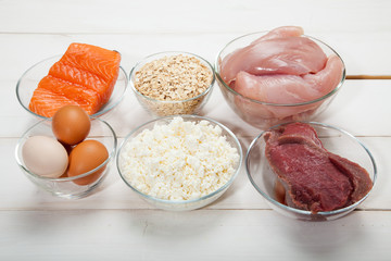 Proteins, fish, cheese, eggs, meat and chicken on a white wooden background