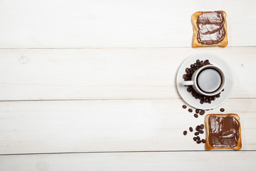 cup of coffee and toast with chocolate on a white wooden table