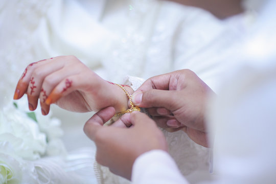 Groom put a jewelry to bride's hand.