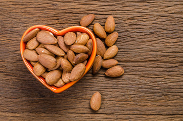 almond in porcelain heart bowl on wooden board