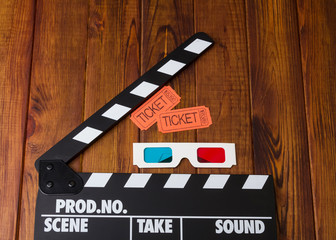 3D-glasses, movie tickets and movie clapper is against dark wood.