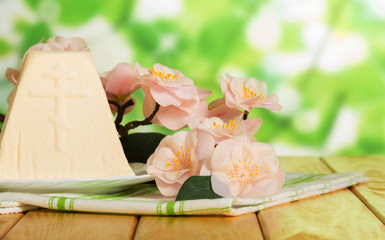 Traditional Easter cheese dessert on fabric napkin, flowers. Abstract green.