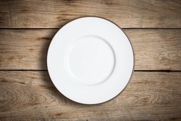Top view of blank white dish on a wood background.