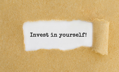 Text Invest in yourself appearing behind ripped brown paper.