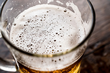 Glass of Beer on dark wooden surface.
