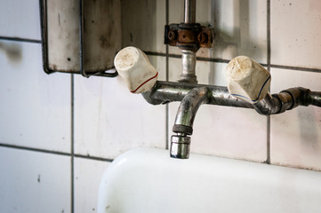 Alter verschmutzter Wasserhahn in Werkstatt