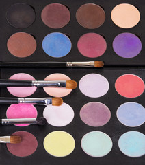 A palette of colorful eye shadow and cosmetic brushes.