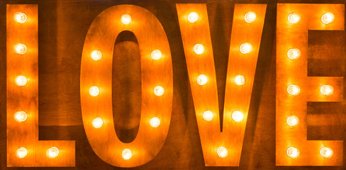 Sign love light bulbs on wooden background.