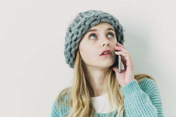 Pretty young girl in sweater, hat with mobile phone