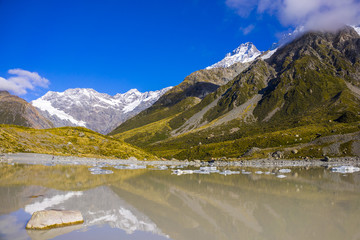 Tasman Glacier Lake with giant floating icebergs, Aoraki Mount Cook National Park New Zealand. Mt Cook looming in the clouds.
