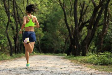 young fitness woman trail runner running in forest