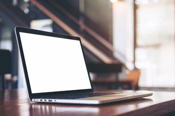 Mockup image of laptop with blank white screen on wooden table in modern loft cafe