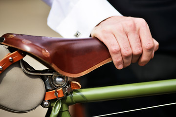 Man in white shirt with his vintage looking bicycle with brown leather saddle