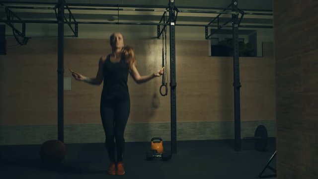Woman jumping with a skipping rope in a gym. Locked down real time 4K video