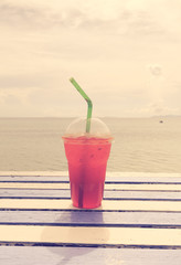 Cold drink on wooden table over summer blue sea,retro effect