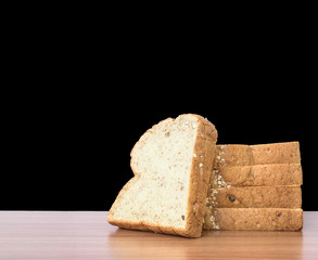Closeup pile of wheat bread for breakfast on brown wood desk isolated on black background
