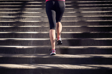 Young woman running up the stairs, unrecognizable person