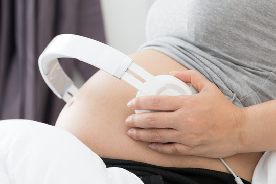 Belly of pregnant women and headphones for listening music