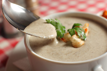 Bowl of cream soup with champignon mushrooms on table
