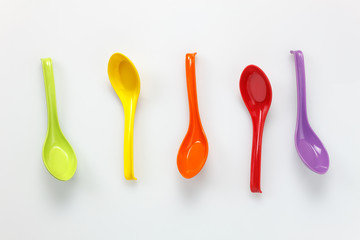 Top view colorful plastic spoon on white table background with copy space.