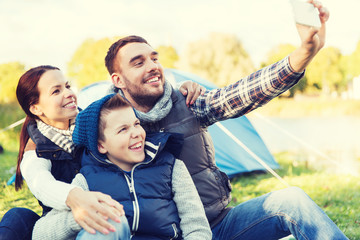 family with smartphone taking selfie at campsite