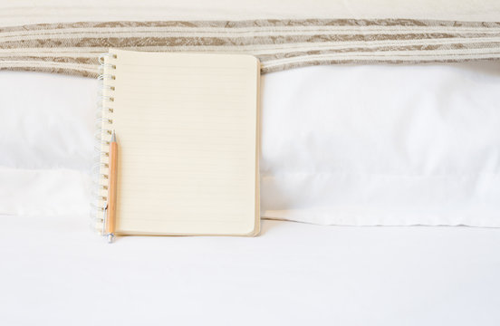 Blank notbook and wood pencil on white bed