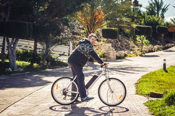 Naklejka premium Ready to ride. Handsome young man on bicycle looking at camera and smiling while standing outdoors