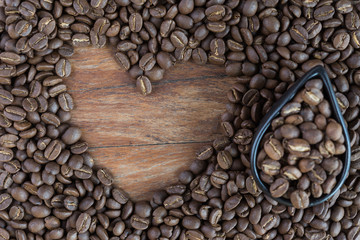 Roasted coffee beans in heart shape on grunge wood background
