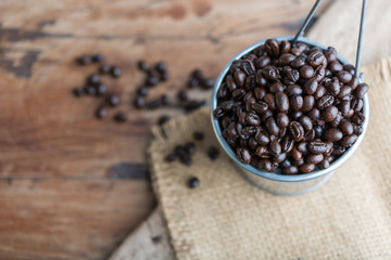 Rosted coffee beans in galvanized pot over grunge  wooden background
