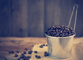 Fototapeta na wymiar Rosted coffee beans in galvanized pot over grunge wooden background