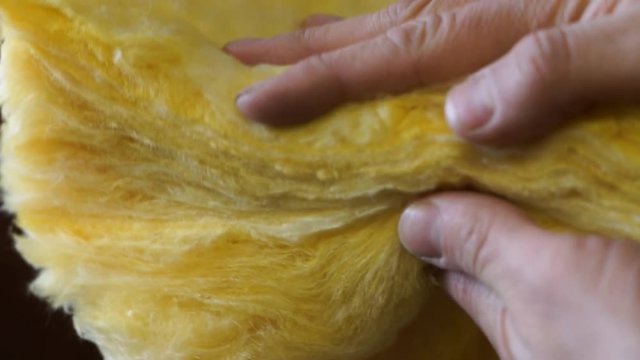 człowiek ściska w dłoniach wełnę mineralną 