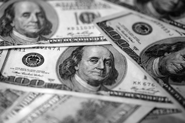Hundred dollar bills on a dark background close up, black and white