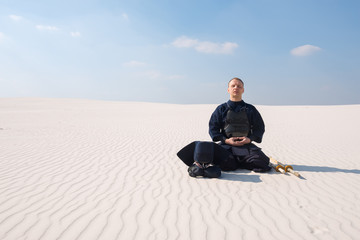 Man in traditional armor for kendo meditates before the practice of martial art