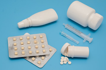 Pills and white bottles of medicine on a blue background. Medical theme and abstraction