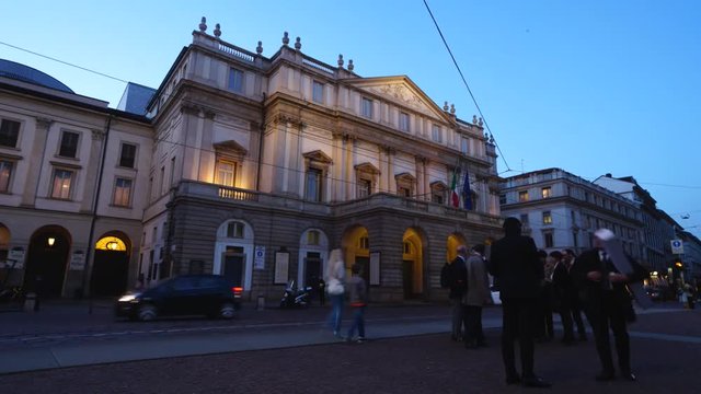 La Scala Theater, opera house in Milan, Italy, in the evening, with car traffic, taxis and trams.
