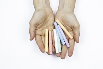 Hands of a woman holding a colored chalks on a white background
