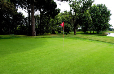 Obraz premium Campo de golf con bandera roja bien cuidado y en primanera