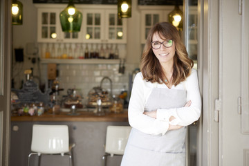 Proud small coffee shop owner businesswoman. Shot of  a happy barista woman standing at doorway and inviting to her coffee shop. Small business. 