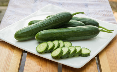 Close up cucumber slice in white dish on wood table.
