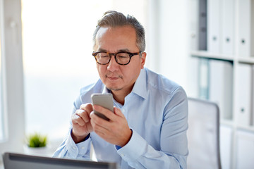 businessman with laptop texting on smartphone