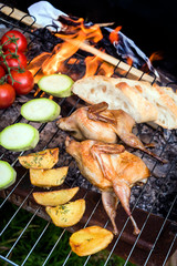 Grilling poultry quails and fresh juicy vegetables in a restaurant