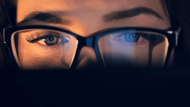 Girl in glasses typing on tablet touch screen. Reflection of tablet in glasses.