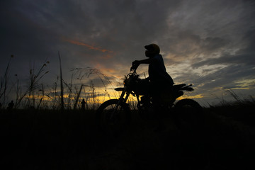 Silhouette of a man riding his motorcycle during sunset.