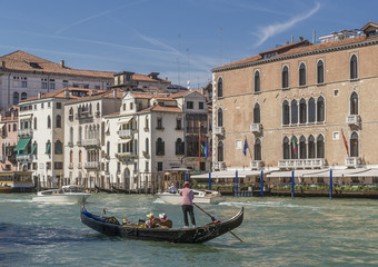 Fototapeta na wymiar A traditional Venetian gondola sailing on the Grand Canal near the Hotel Gritti Palace, Venice, Italy